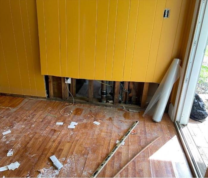 An orange kitchen wall is partially demolished after a water damage.