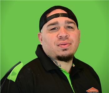 A male SERVPRO employee smiles infront of a green background.