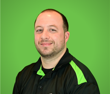 A male SERVPRO employee smiles infront of a green background.