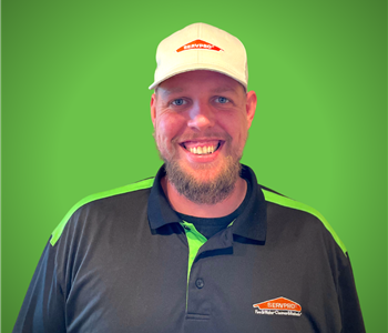 A male servpro employee smiles infront of a green background.