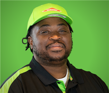 A male servpro employee smiles infront of a green background.