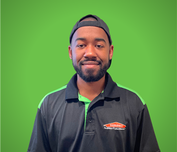 A male servpro employee smiles infront of a green background.