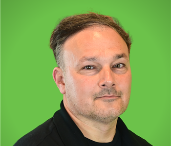 A male SERVPRO employee smiles infront of a green background.