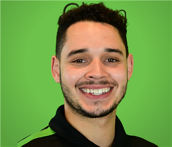 A male SERVPRO employee smiles infront of a green background.