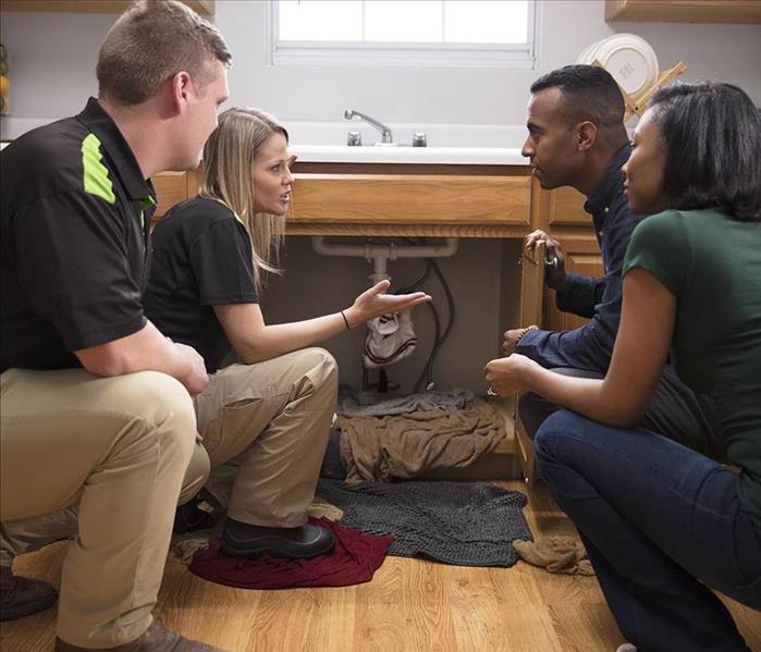 Two SERVPRO technicians speak with a couple in the kitchen of their home.