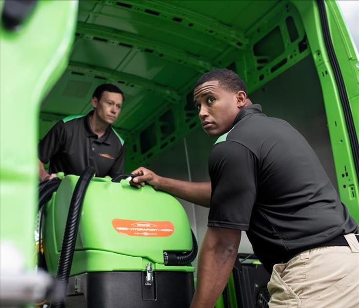 Two SERVPRO employees unload equipment from a van.