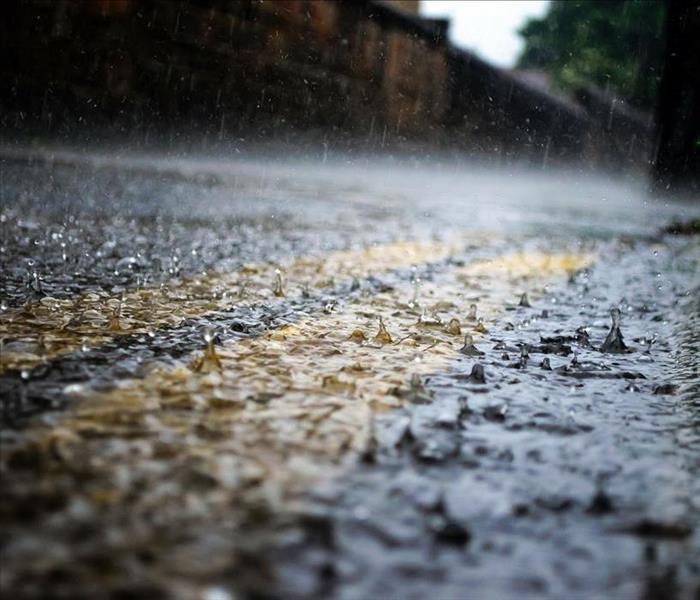 Rain water splashes on a paved road.