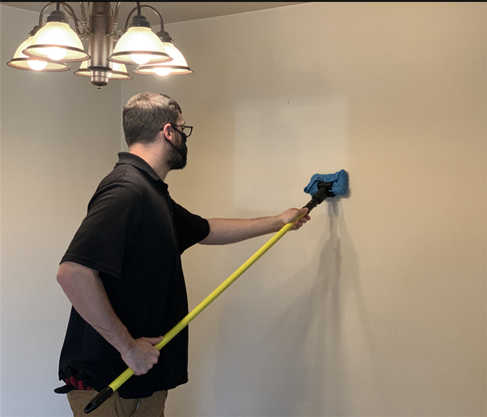 SERVPRO technician scrubs stains from a rental unit wall.